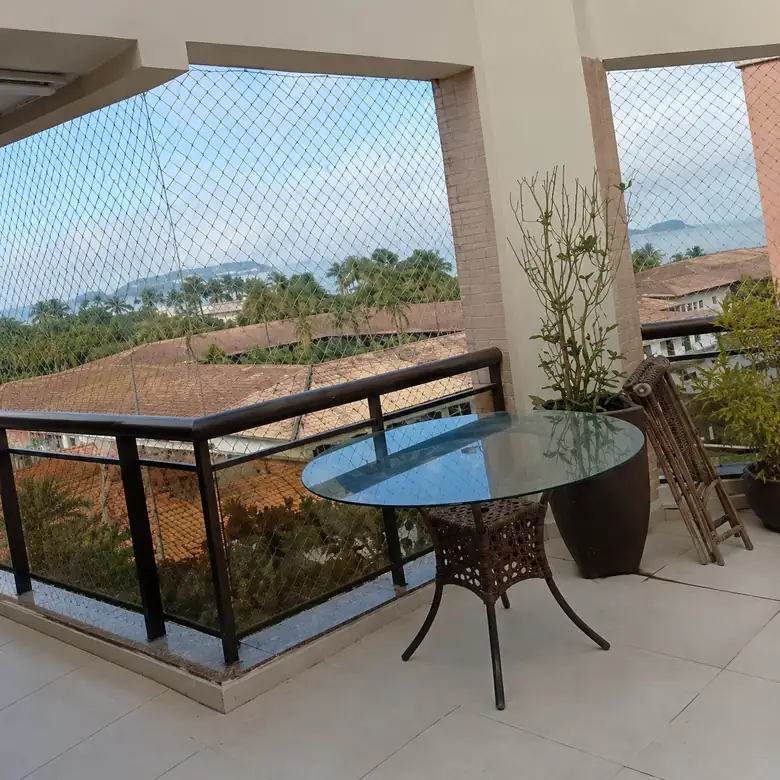 Varanda com guarda-corpo de vidro e mesa, vista para os telhados