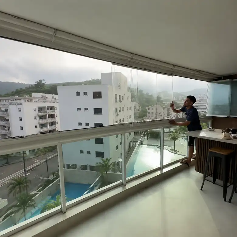 Sacada envidraçada em apartamento com vista para a piscina do prédio